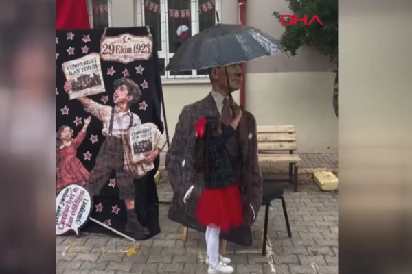 Atatürk maketini yağmurdan şemsiyeyle korudu